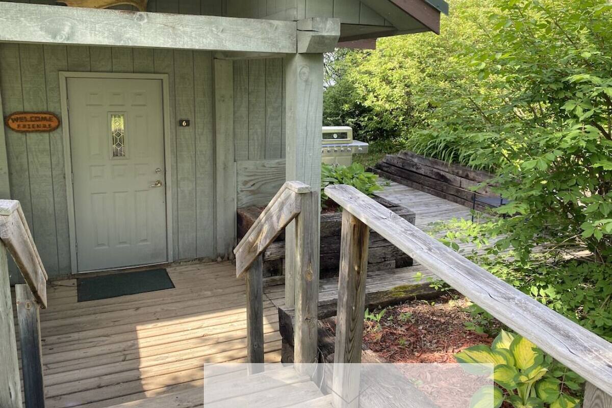 A wooden cabin with a porch, a welcome sign, and a number '6' on the door.