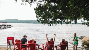A lakeside scene with red Adirondack chairs and a dock. - Gunflint Lodge & Outfitters (Grand Marais)