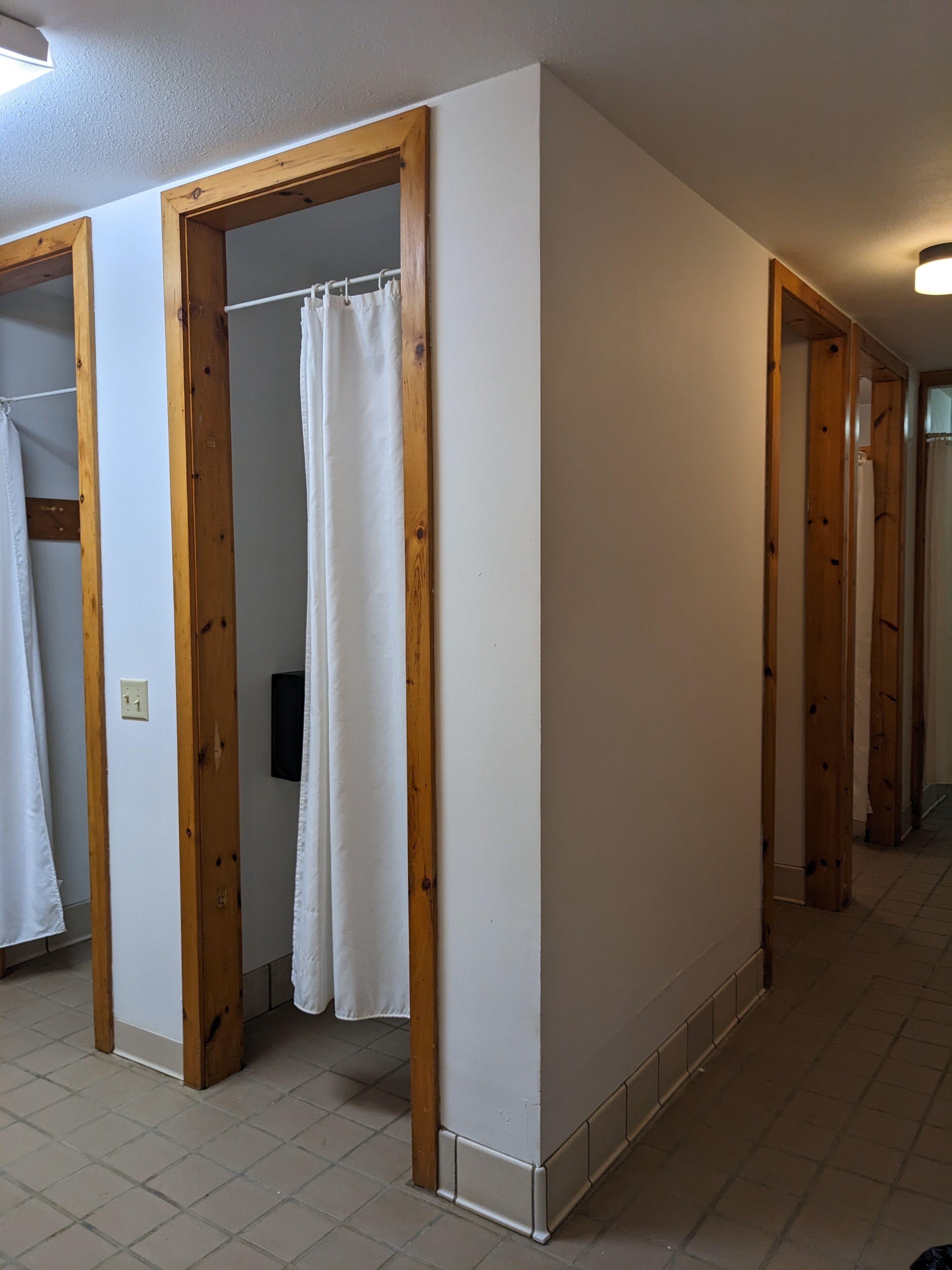 A hallway with wooden doors and a white curtain in a room.