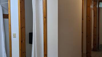 A hallway with wooden doors and a white curtain in a room.