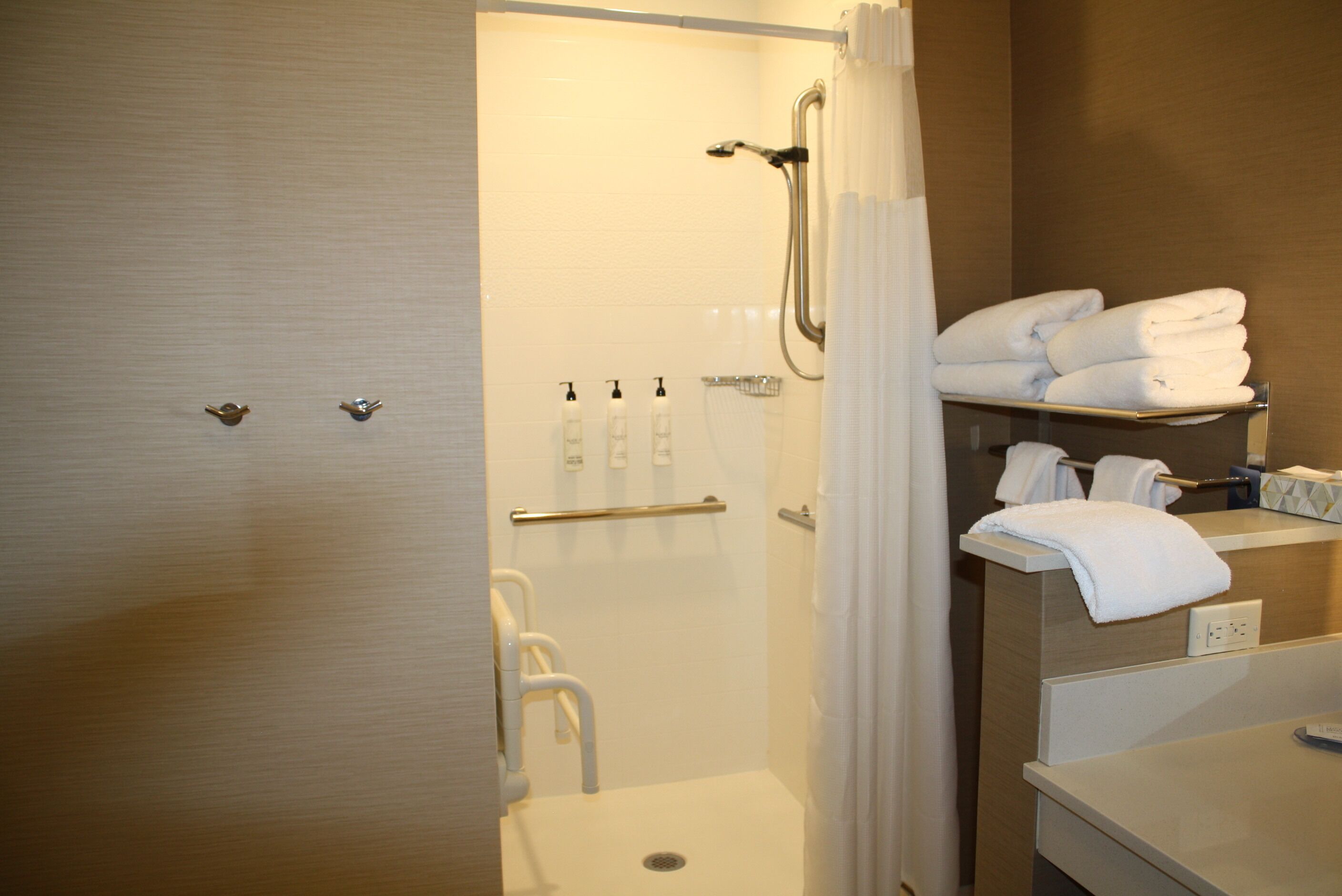 A bathroom with a shower, toilet, and sink. There are towels and toiletries on the counter.