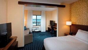A hotel room with a bed, a desk, a TV, a chair, and a view of the sea. - Fairfield Inn & Suites by Marriott Detroit Lakes (Detroit Lakes)