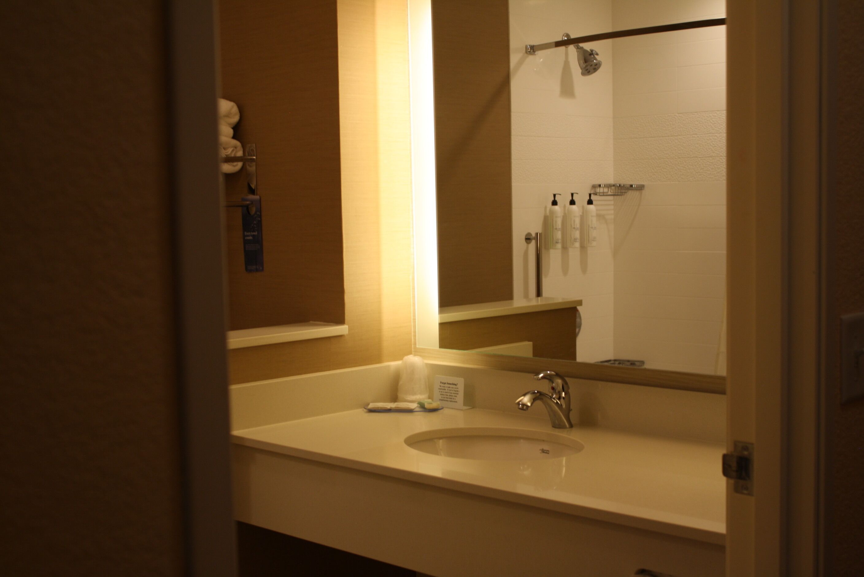 A bathroom with a sink, mirror, and toiletries.