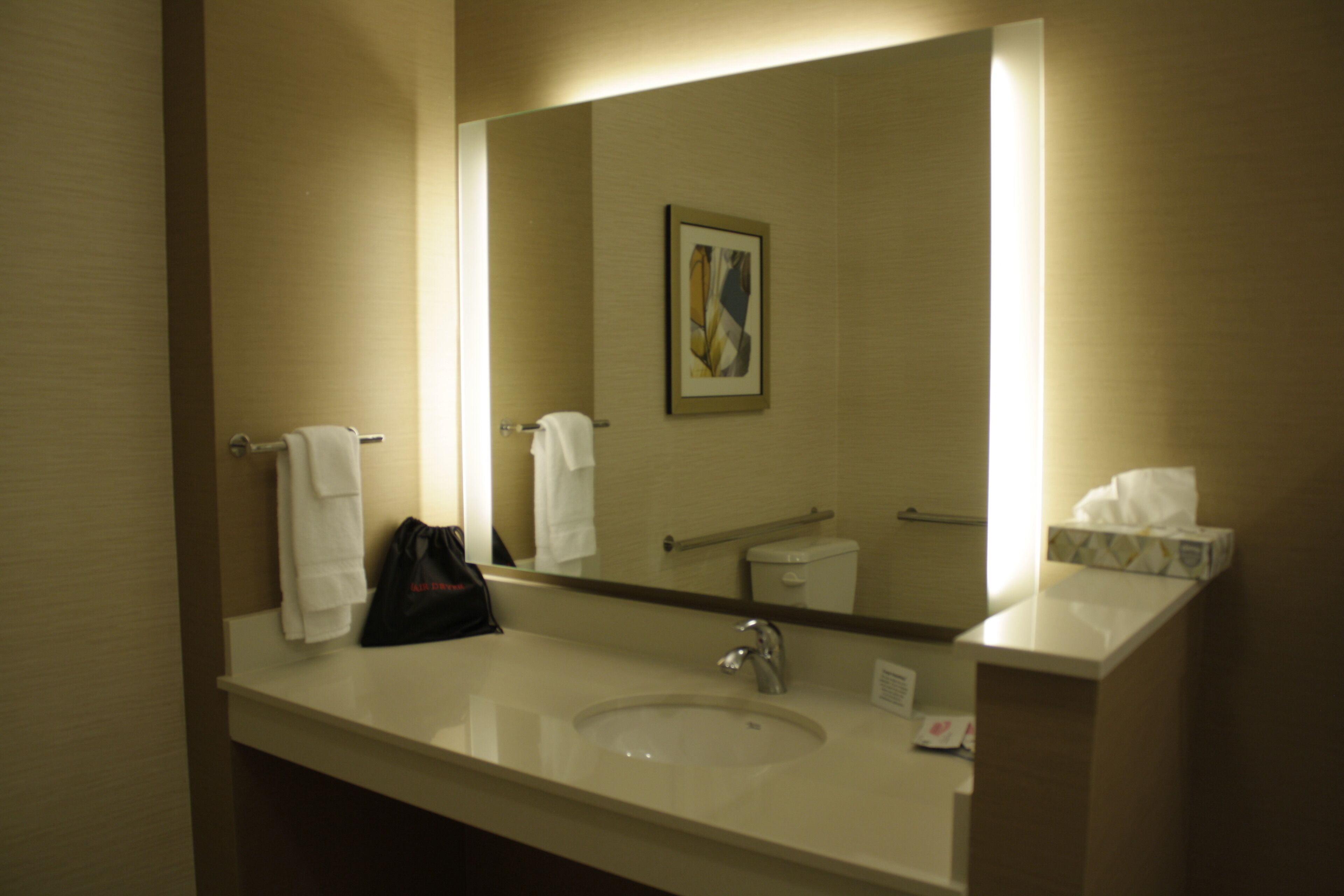 Een hotelbadkamer met een grote spiegel, een wastafel en een handdoekhouder.