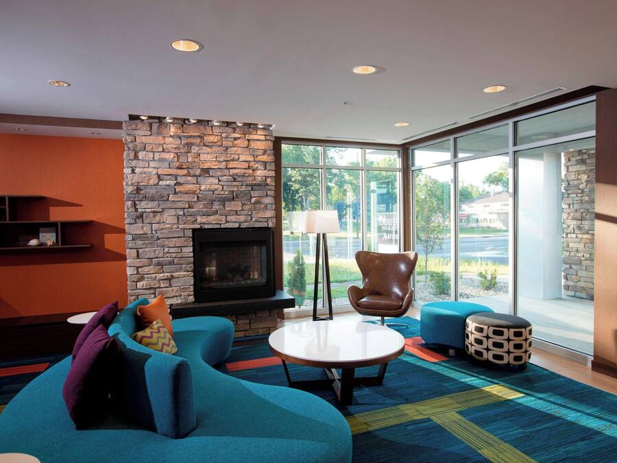 A modern living room with a stone fireplace, comfortable seating, and large windows offering a view of the outdoors.