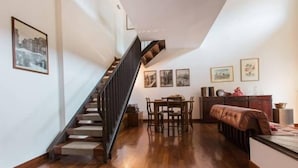 A modern interior with a wooden staircase, a dining area with a table and chairs, and a sofa.