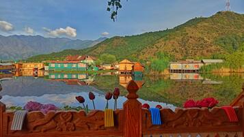 A riverside village with traditional houses, a mountain backdrop, and a prominent communication tower.