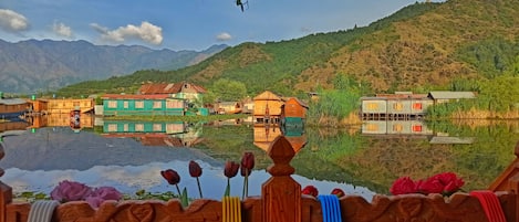 A riverside village with traditional houses, a mountain backdrop, and a prominent communication tower.