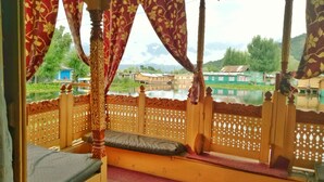 Quarto com cama de madeira, vista para um corpo d'água e guarda-corpo de madeira.