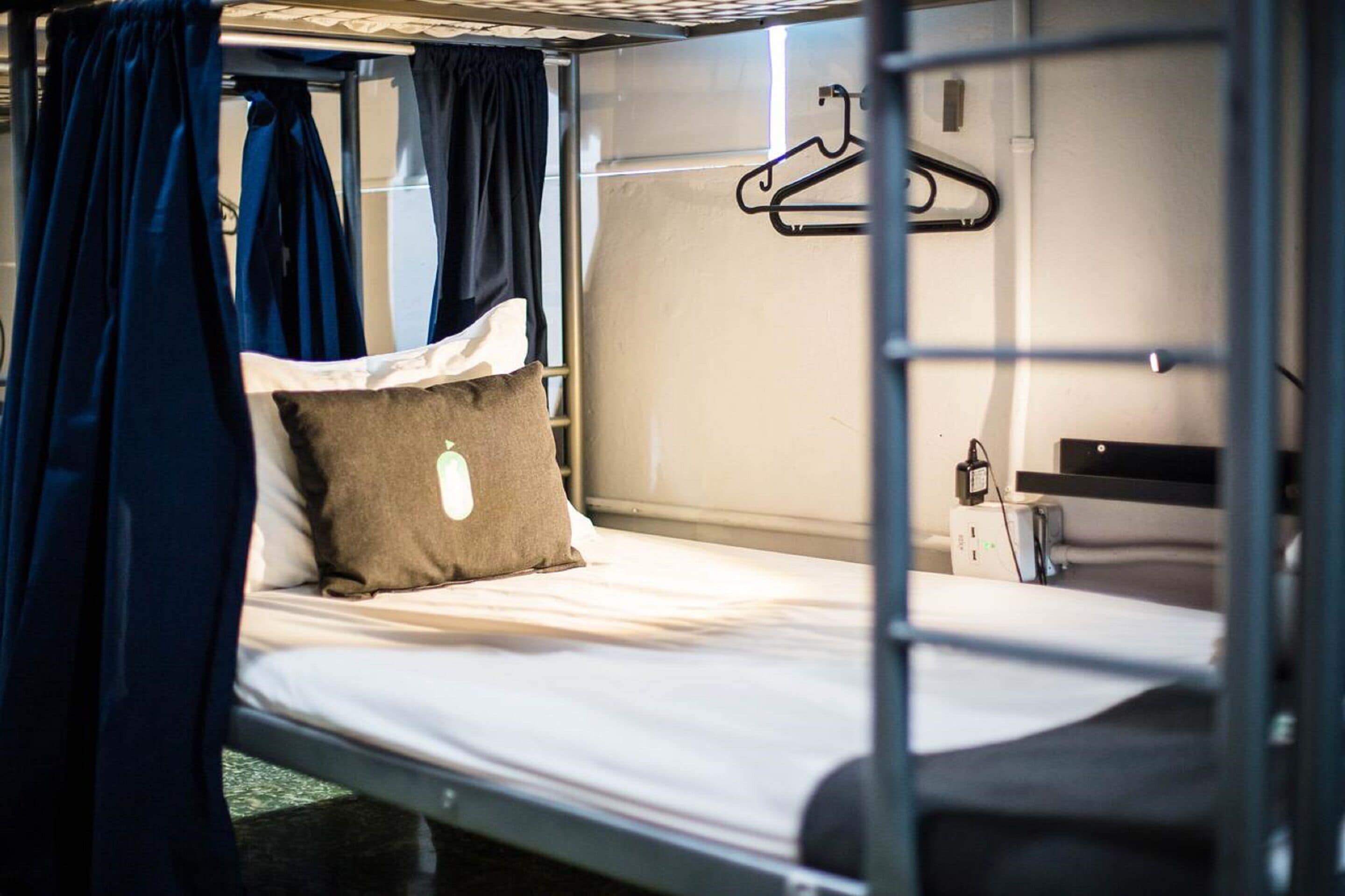 Een stapelbed met een kledingroede en een klein bureau met een computer.