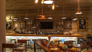 A bar area with wooden ceiling, hanging pendant lights, and a bar counter with various bottles and glasses.