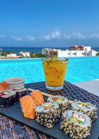 Una mesa con sushi, una bebida y vista al océano.