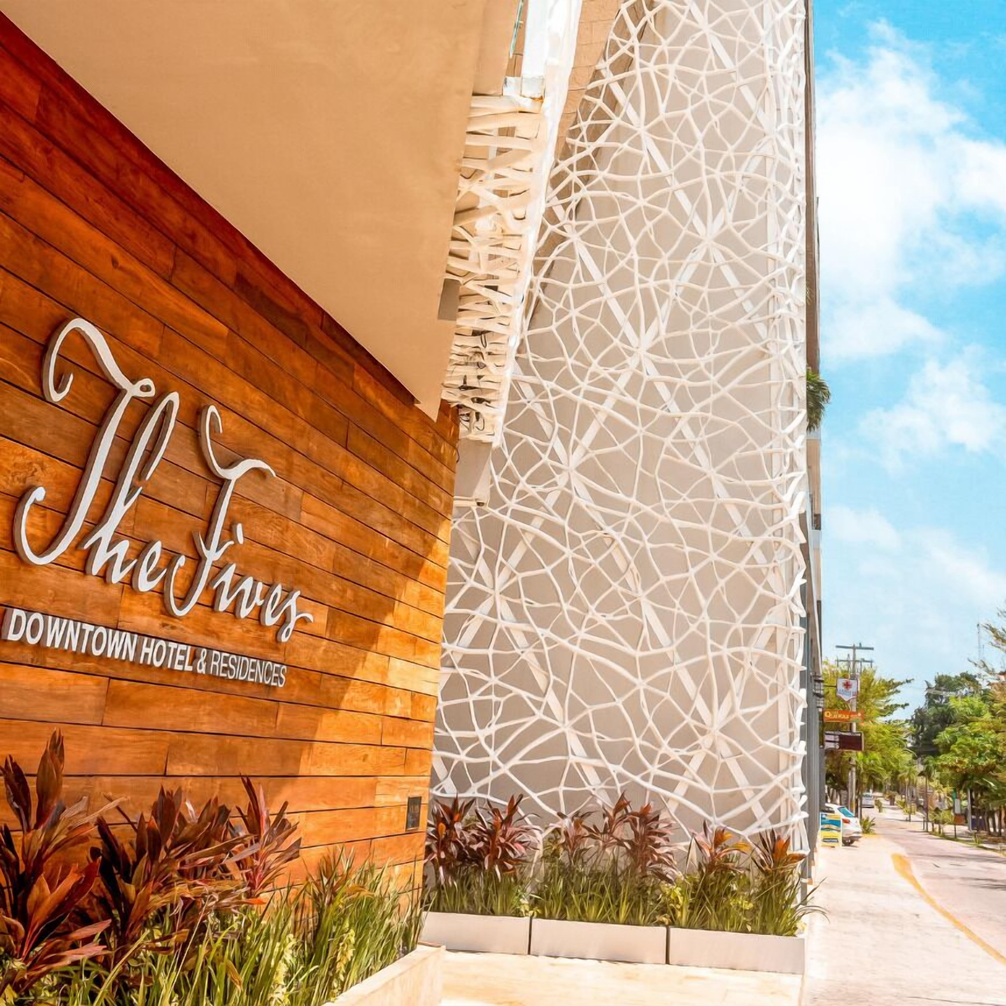 Fachada de hotel con diseño de paneles de madera y una estructura de celosía blanca decorativa.