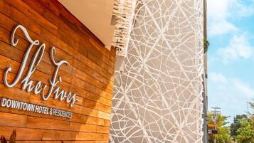 Fachada de hotel con diseño de paneles de madera y una estructura de celosía blanca decorativa.