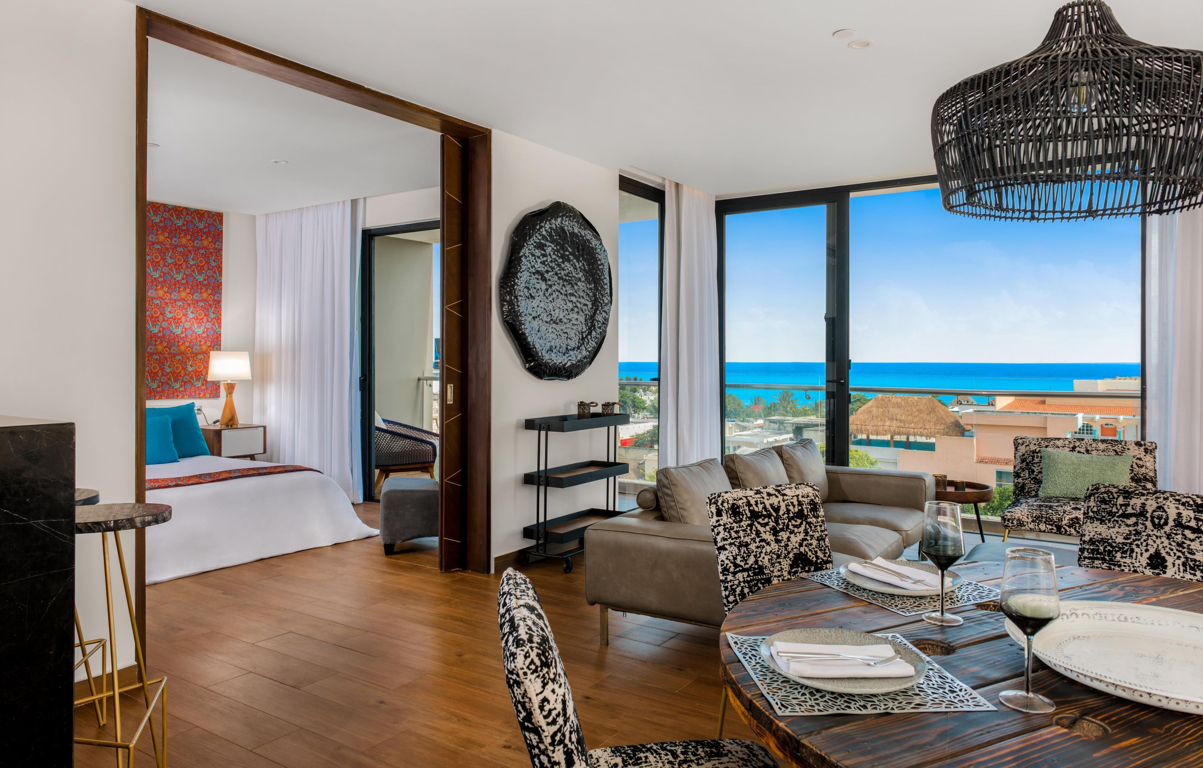 Habitación de hotel moderna con balcón amplio, zona de comedor y vistas al mar.