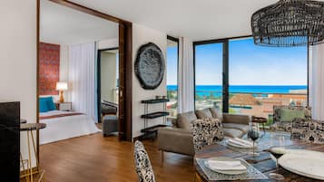 Habitación de hotel moderna con balcón amplio, zona de comedor y vistas al mar.