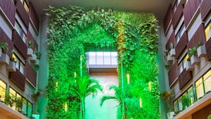 A modern atrium with a central fire feature, green vertical gardens, and a wooden deck.