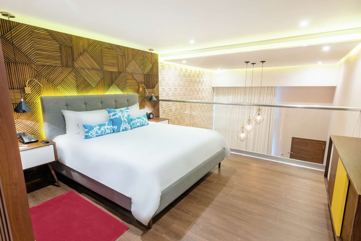 Ein modernes Schlafzimmer mit einem großen Bett, einem Holzkopfteil, einem roten Teppich und einem Balkon mit Geländer.
