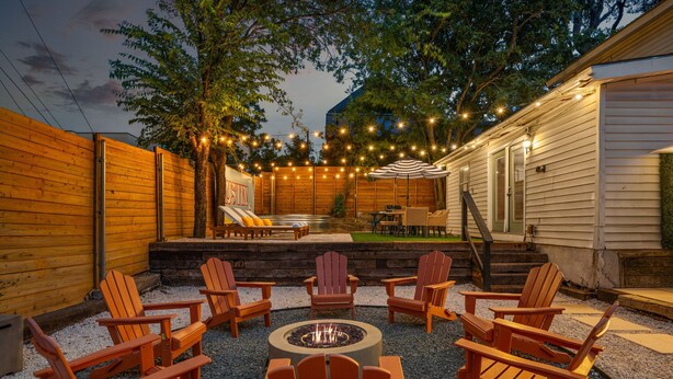 An outdoor patio with Adirondack chairs, a fire pit, and string lights. - Huge Bachelor/ettes & family property w/ 2 Homes, Pool, Games, close to Downtown (Austin)