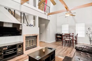 Cozy living area with a high ceiling, fireplace, and large flat-screen TV.