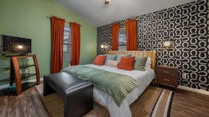 A bedroom with a bed, a ceiling fan, a nightstand, a TV on a stand, and patterned wallpaper. - Huge Bachelor/ettes & family property w/ 2 Homes, Pool, Games, close to Downtown (Austin)