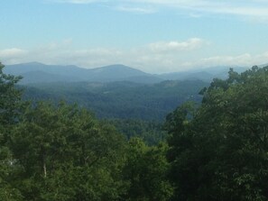 Eine gebirgige Landschaft mit dichtem Wald im Vordergrund und weit entfernten Hügeln.