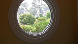 Una ventana redonda con vistas a un jardín y casas.