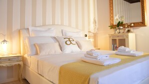 Une chambre d’hôtel avec un grand lit, une table de chevet avec une lampe, un miroir et des serviettes soigneusement pliées sur le lit.
