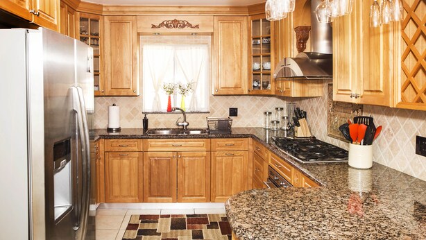A kitchen with wooden cabinets, a stainless steel refrigerator, a granite countertop, and hanging wine glasses. - Waterfront Home, Large Heated Pool, 5 min. from the beach, family friendly (Pompano Beach)