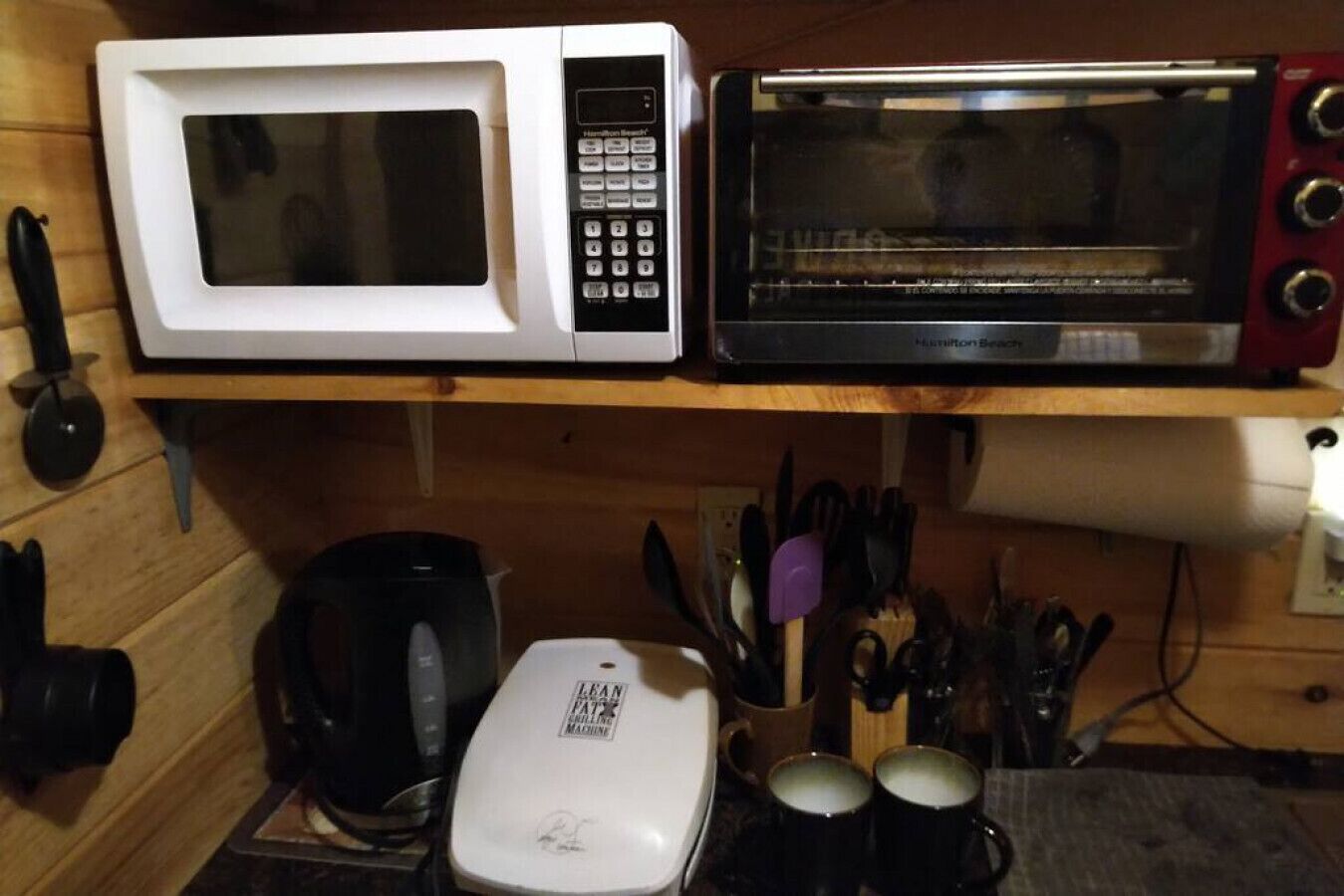 Eine Küche mit einer weißen Mikrowelle, einem schwarzen Toaster und einer Kaffeemaschine auf der Arbeitsfläche.
