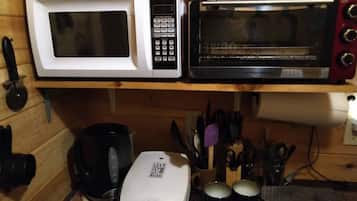 Eine Küche mit einer weißen Mikrowelle, einem schwarzen Toaster und einer Kaffeemaschine auf der Arbeitsfläche.