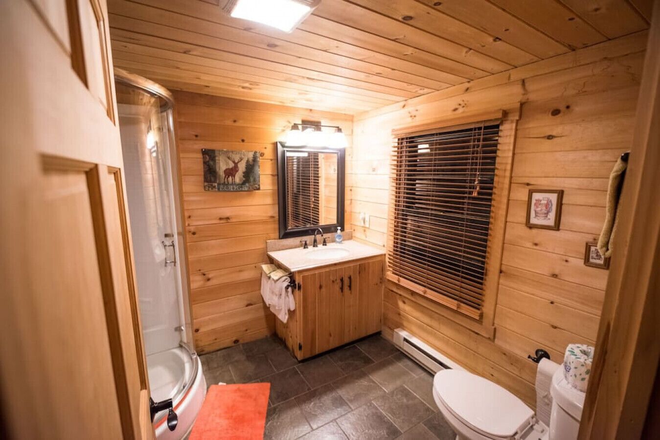 A wooden cabin bathroom with a shower, toilet, and sink.