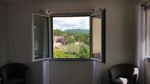 Una habitación con un ventanal grande que ofrece vistas a un paisaje verde con árboles y colinas.