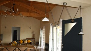 Un salón amplio con techo de madera, una mesa de comedor con sillas, un sofá con cojines y una puerta negra con espejo.