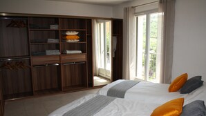 Un dormitorio con dos camas, un armario y un balcón.