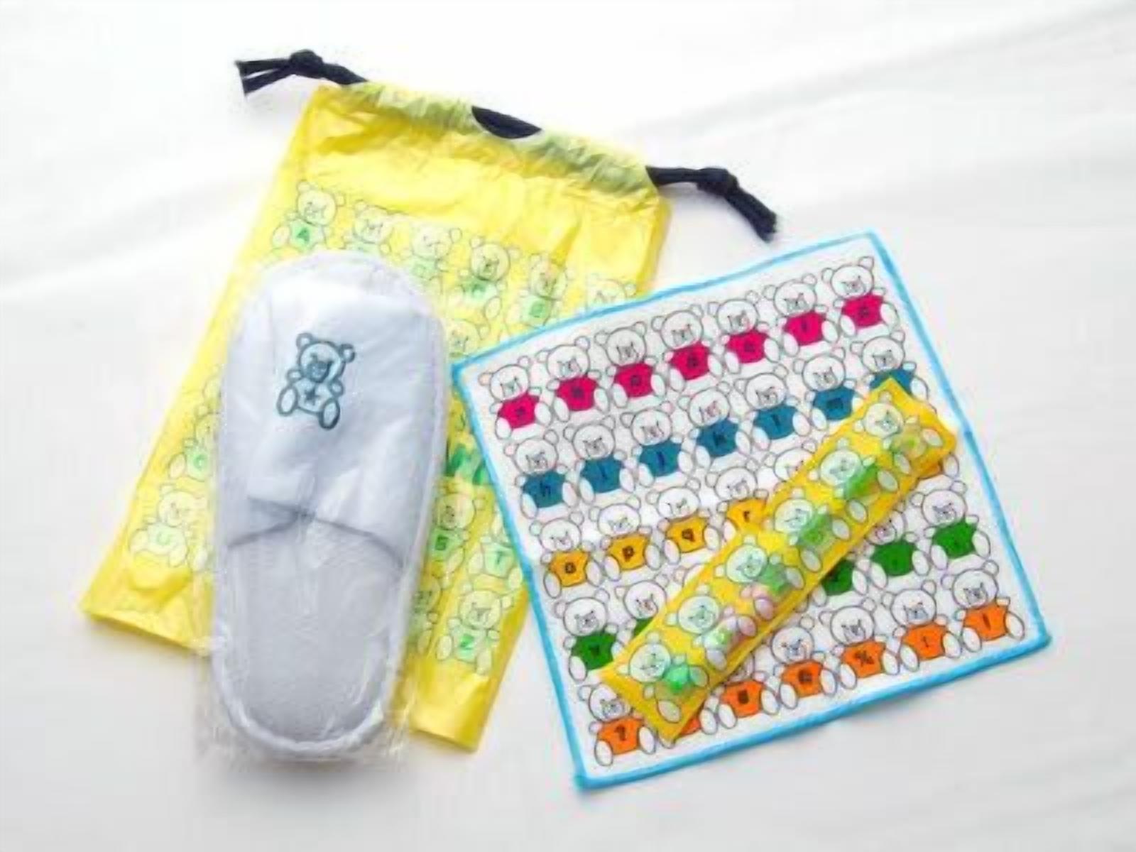 A yellow drawstring pouch with a teddy bear design, a white pouch with a bear design, and a sheet of stickers with bear designs.