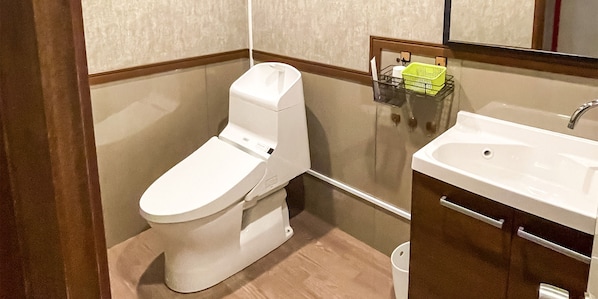 A bathroom with a white toilet, a sink, and a mirror.