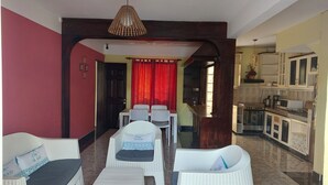 Ein Wohnzimmer mit Essbereich, Küche und einem roten Vorhang.