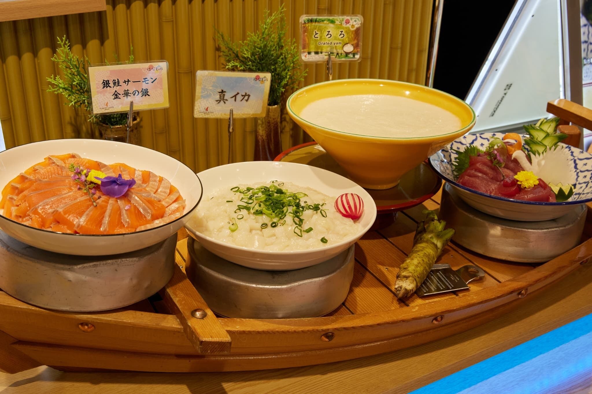 A traditional Japanese meal setup with various dishes, including sashimi, rice, and soup, displayed on a wooden boat.