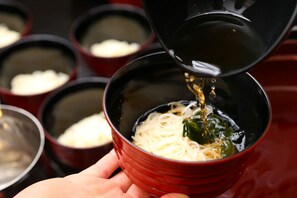 Un tazón de fideos al que se vierte un líquido, probablemente caldo.