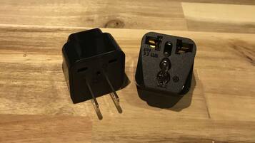 Two black power adapters on a wooden surface.