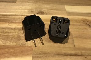 Dos adaptadores de corriente negros sobre una superficie de madera.