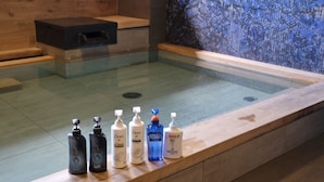 A glass-enclosed hot tub with a wooden bench and a tiled wall. - Almont Hotel Sendai (Sendai)
