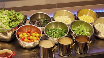 Ein Buffet mit verschiedenen Speisen in Metallschüsseln und -töpfen, darunter Salate, Gemüse und weitere Gerichte.