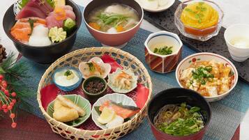 Variedad de platos japoneses, incluyendo sashimi, sopa y fideos, dispuestos sobre una mesa con un mantel tejido.
