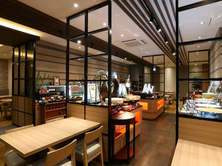 L’intérieur d’un restaurant, avec des meubles en bois, un espace buffet et un coin salon.