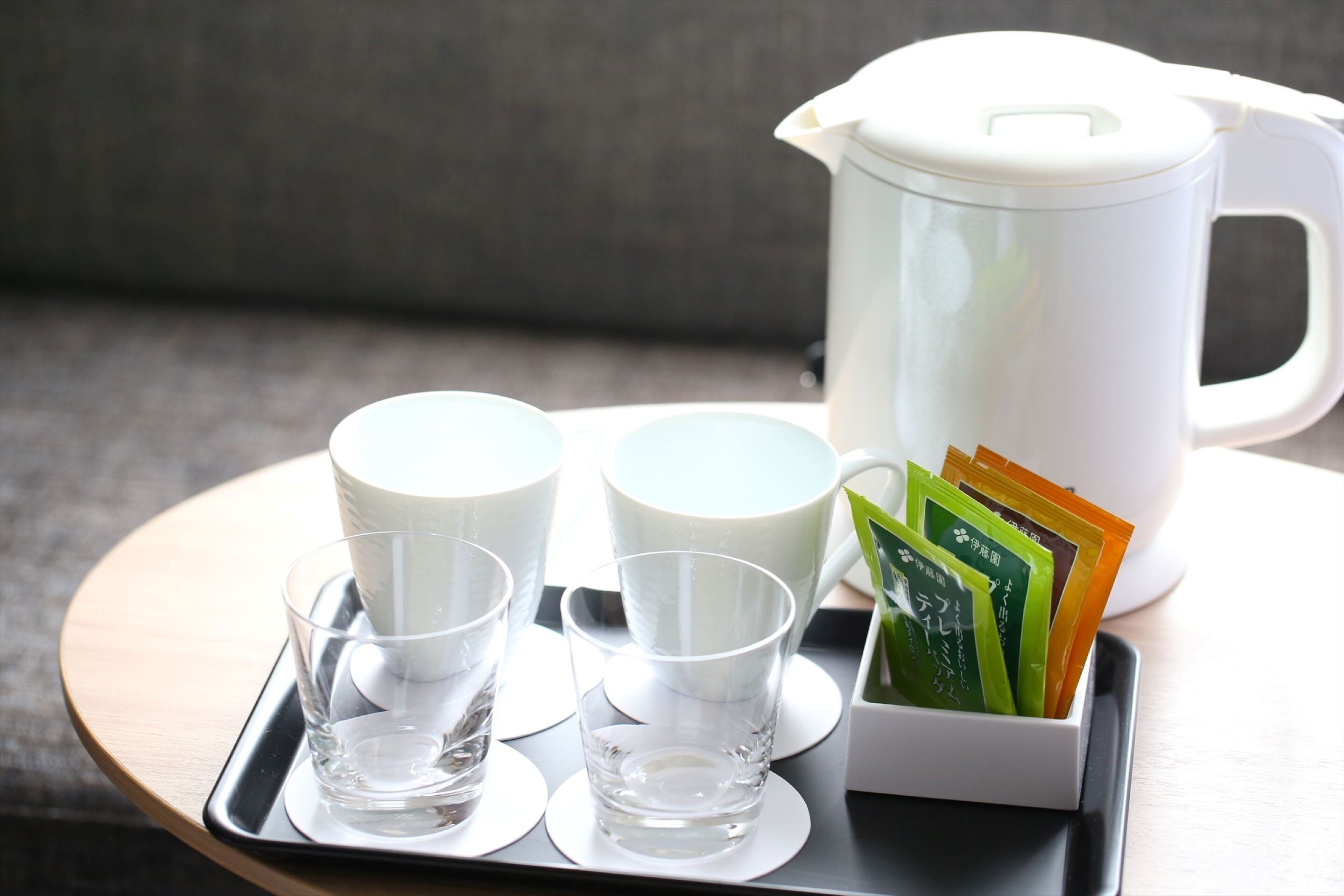 Una bandeja con una jarra blanca, dos tazas y un soporte para sobre de té.
