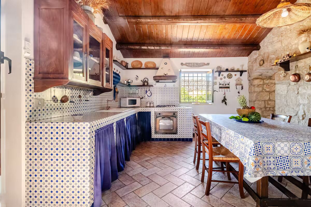 A kitchen with wooden cabinets, a tiled backsplash, and a dining area with a table and chairs.