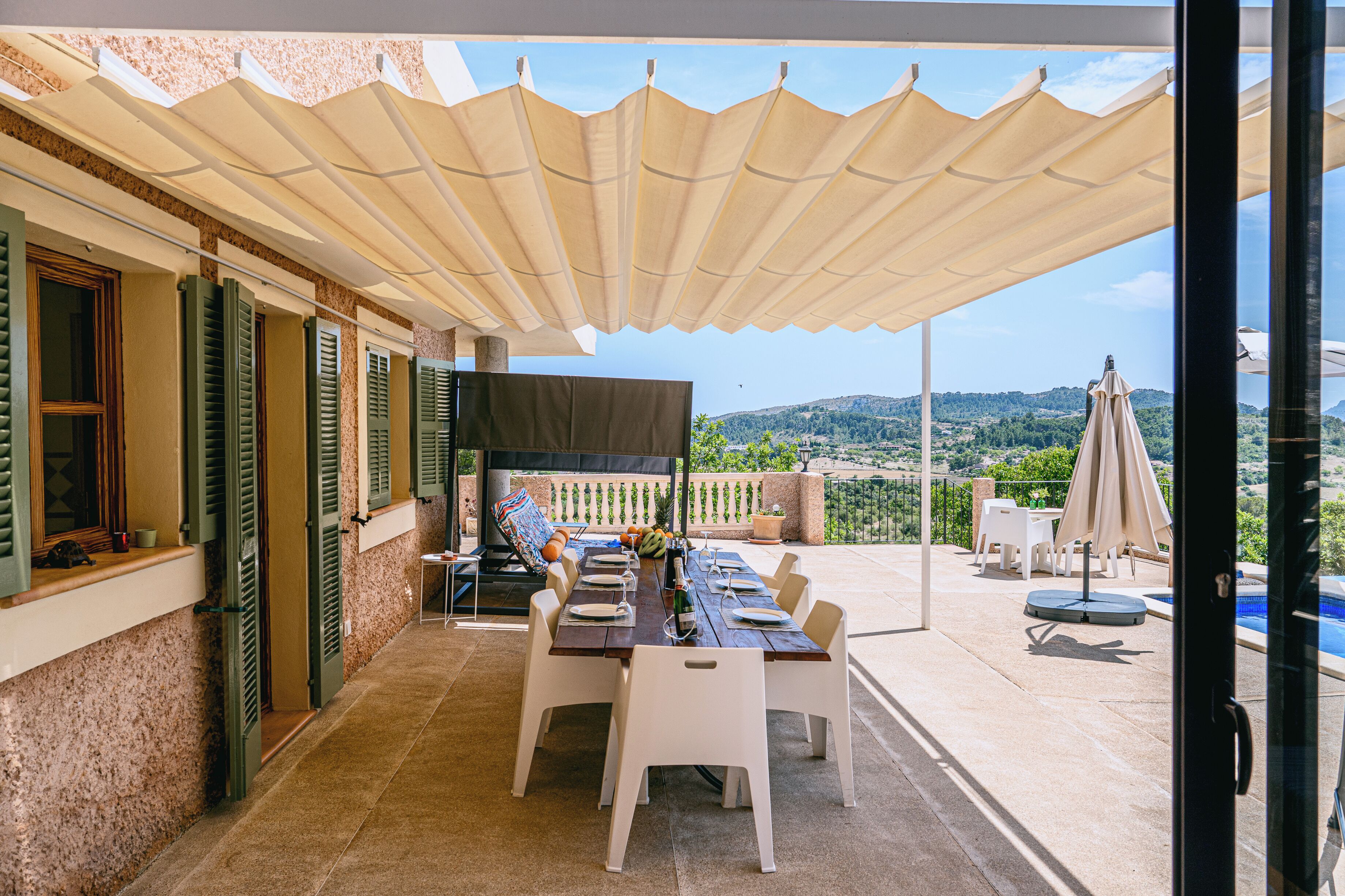 An outdoor dining area with a table set for four, a pool, and a view of the landscape.