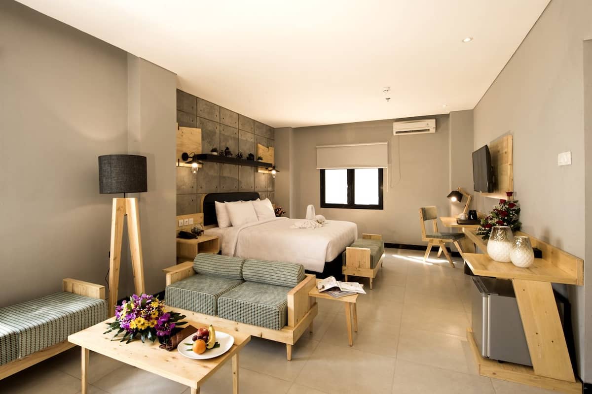 Una habitación de hotel moderna con cama, zona de estar, escritorio y televisor.